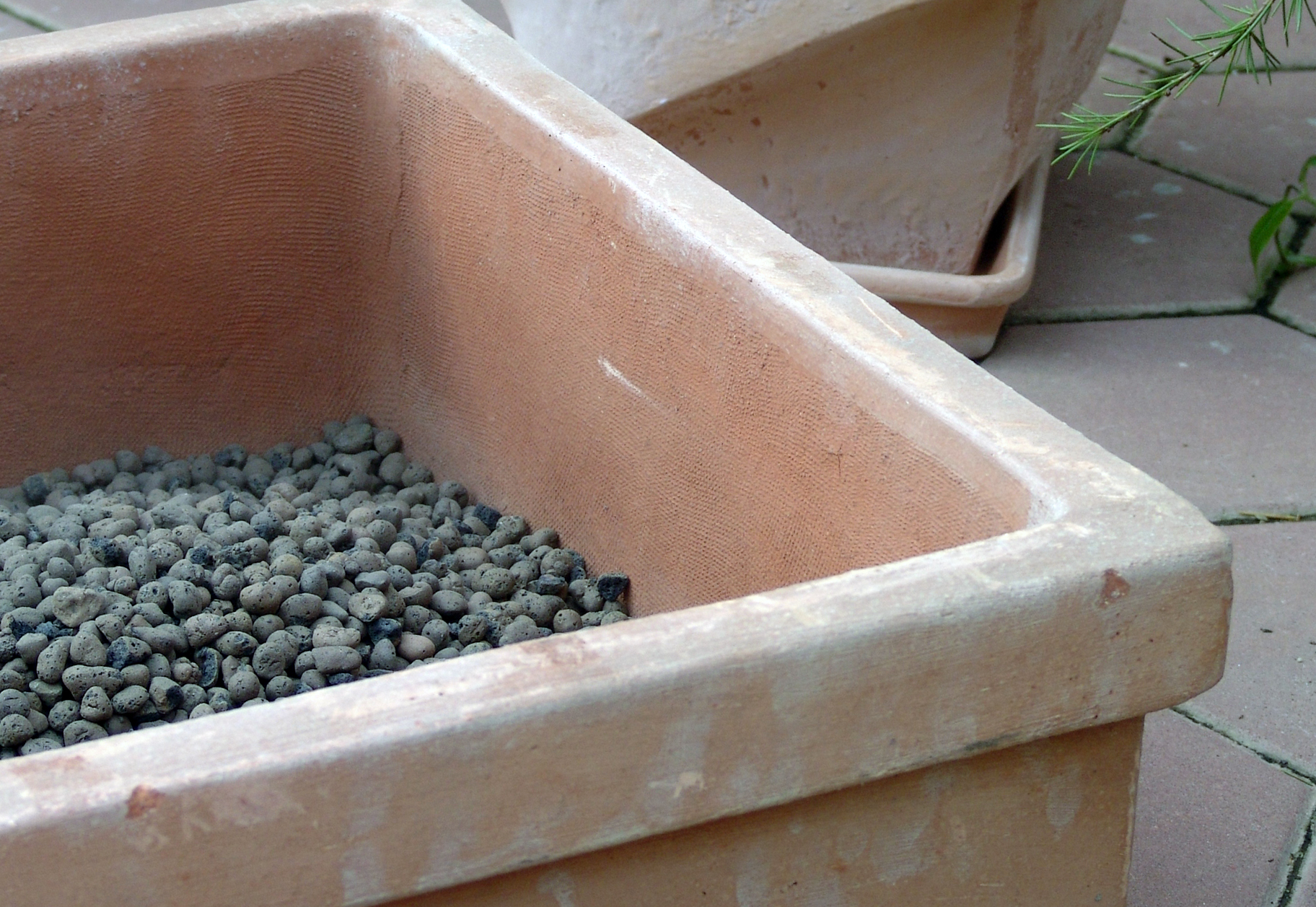 Preden položimo agrokopreno ali juto, v lonec nasujemo drenažno plast