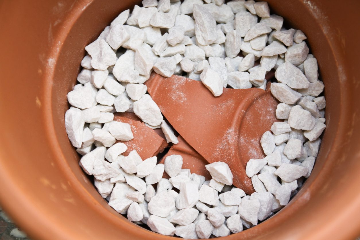 Drenažni sloj iz črepinje in kamenja na dnu keramične posode